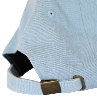 Back of the light denim baseball hat showing the adjustable antique brass metal buckle closure