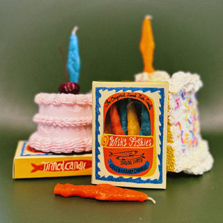 Wishy Fishies sardine-shaped cake candles in an illustrated tin-style box by Tinned Candle, with faux cakes topped with blue and orange fish candles