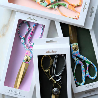 Set of colorful scissors with floral patterns in packaging on a marble surface