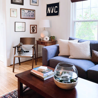 Navy NYC peace pennant displayed on a white living room wall above a wood side table