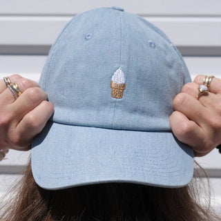 Light denim Idlewild soft serve ice cream cone baseball hat held up front-on, embroidered cone on the crown