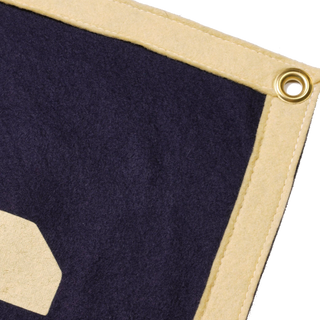 Corner detail showing the cream felt border, stitching, and brass hanging grommet