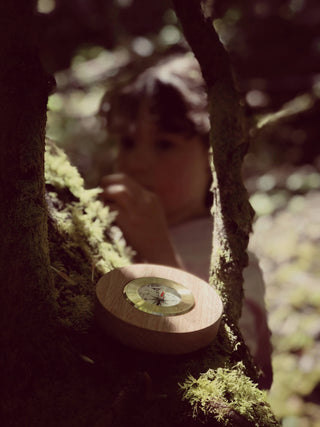 Black walnut and brass working compass held in hand, sized for a child — nature play and outdoor exploration — Wren Supply Co.