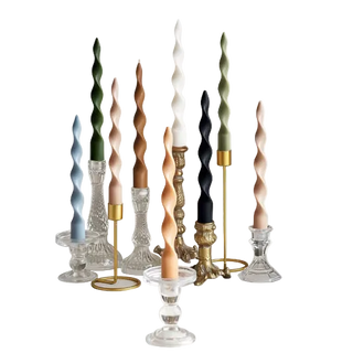 Twisted spiral taper candles in ivory, olive, caramel, milk tea, and smoke blue, arranged in brass and glass holders.