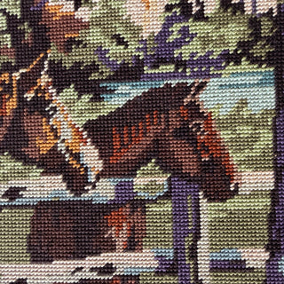 Close-up of the needlepoint stitching at the horses' heads over the fence rail, worked in dark brown, chestnut, cream and blue