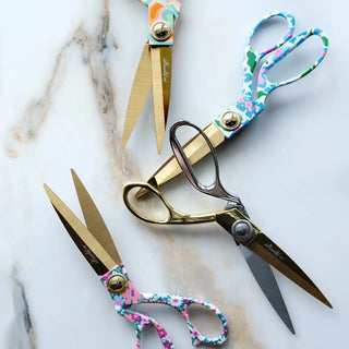 Three pairs of scissors with floral handles on a marble surface